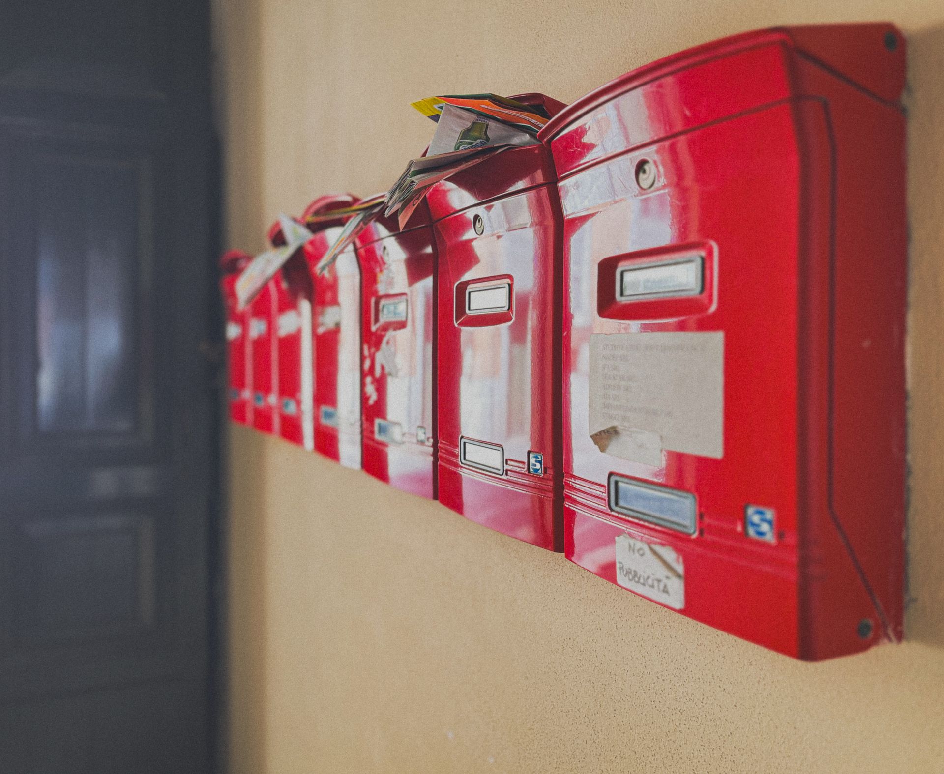 Row of red mailboxes overflowing with unread mail